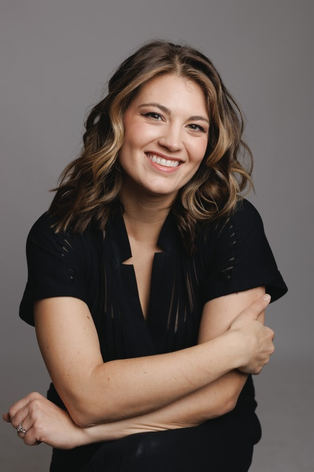 Young woman with long brown hair, black outfit, smiling